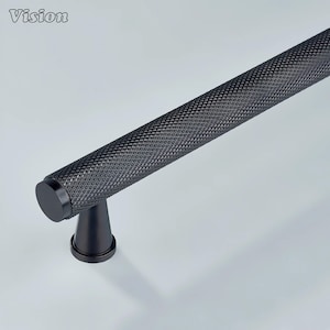 May include: Black textured cabinet pull with a diamond pattern. The pull is cylindrical with a flat end cap and is mounted on a conical base. The word "Vision" is in the top left corner.