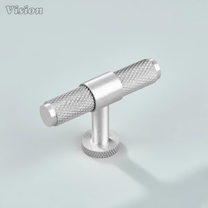 May include: A silver-colored cabinet pull with a textured, diamond-patterned handle. The pull has a cylindrical shape with a round base and a short stem. The word "Vision" is in the upper left corner.