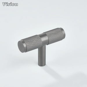 May include: A gray, T-shaped cabinet pull with a textured, diamond-patterned handle. The handle is cylindrical with a flat end. The pull is made of metal and has a matte finish. The word "Vision" is in the top left corner.
