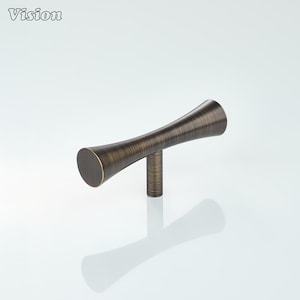 May include: Bronze-toned cabinet pull with a cylindrical base and a curved, elongated handle. The handle has a textured surface and a slight hourglass shape. The word "Vision" is in the upper left corner.