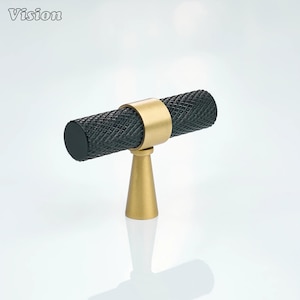 May include: A black and gold cabinet pull with a textured, cylindrical handle and a gold-colored base. The handle is secured by a gold ring. The word "Vision" is in the top left corner.