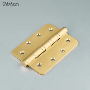May include: A brass door hinge with rounded corners and multiple screw holes. The hinge is in an open position, showing the cylindrical pin that connects the two rectangular plates. The word "Vision" is in the top left corner.