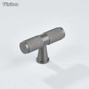 May include: A gray cabinet pull with a diamond pattern on the handle. The pull has a T-shape design with a cylindrical handle and a conical base. The word "Vision" is in the upper left corner.