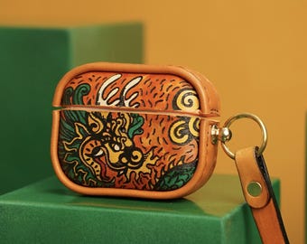 May include: A brown leather Airpods case with a colorful dragon design. The case has a strap with a gold ring.