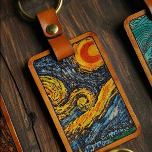 May include: A leather keychain with a brass ring and a rectangular leather tag featuring a printed image of Vincent van Gogh's "Starry Night" painting.
