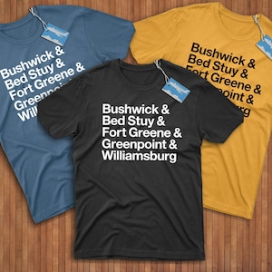 May include: Three t-shirts with different colors and the text "Bushwick & Bed Stuy & Fort Greene & Greenpoint & Williamsburg" printed on them.