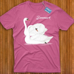 May include: Pink t-shirt with a graphic of two white swans in a heart shape. The text "Denmark" is printed on the shirt.