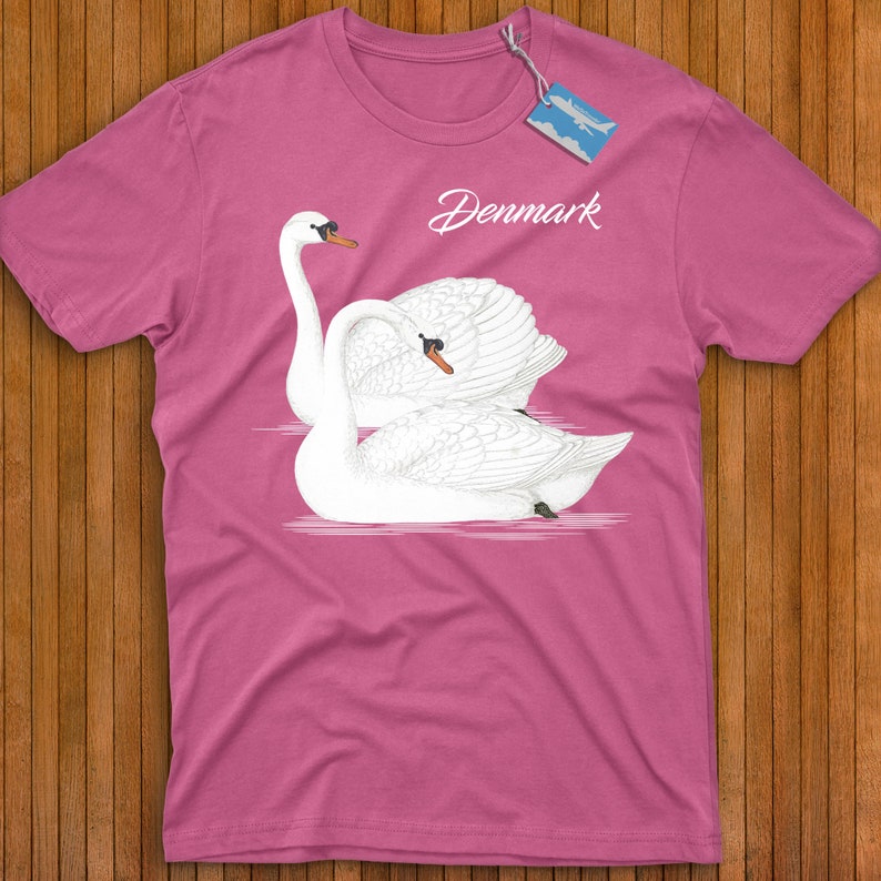 May include: Pink t-shirt with a graphic of two white swans in a heart shape. The text "Denmark" is printed on the shirt.
