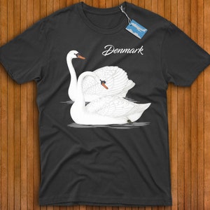 May include: A dark gray t-shirt with a white graphic of two swans. The text "Denmark" is printed in white above the swans.