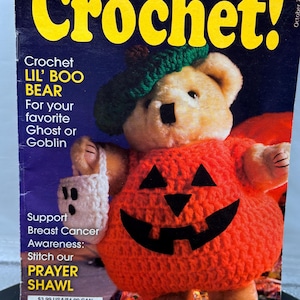 May include: A crochet pattern book cover featuring a crocheted bear wearing a pumpkin costume and a green hat. The text reads "Hooked on Crochet!" and "Crochet Lil' Boo Bear". The cover also promotes a prayer shawl for breast cancer awareness.