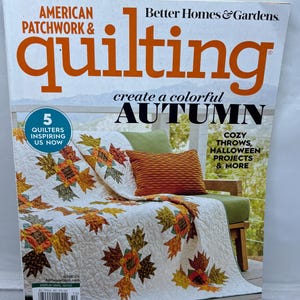 May include: The cover of "American Patchwork & Quilting" magazine features a quilt with autumn leaf patterns. The magazine's title is in orange and white, with the words "create a colorful AUTUMN" below. The cover also mentions "Cozy Throws, Halloween Projects & More."