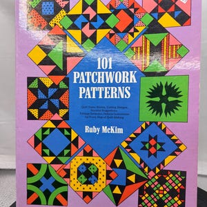 May include: A softcover book titled 101 Patchwork Patterns by Ruby McKim with a light purple cover featuring a central blue diamond containing the title and text, surrounded by a colorful grid of various geometric quilt block designs.