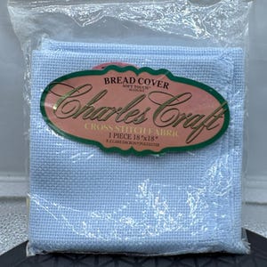 May include: A light blue Charles Craft cross stitch fabric bread cover measuring 18 inches by 18 inches. The fabric is 14 count and made of E-Z Care Dacron and polyester. It is packaged in a clear plastic bag with a label.