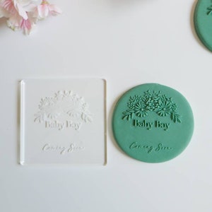 May include: A green silicone stamp with a floral design and the text "Baby Boy Coming Soon".