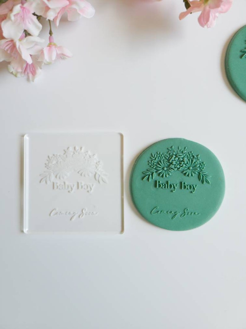 May include: A green silicone stamp with a floral design and the text "Baby Boy Coming Soon".