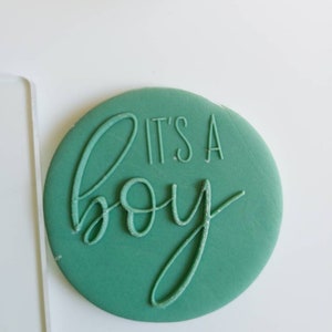 Op de afbeelding: Een ronde sticker in tealblauw met de tekst "It's a boy" in wit.