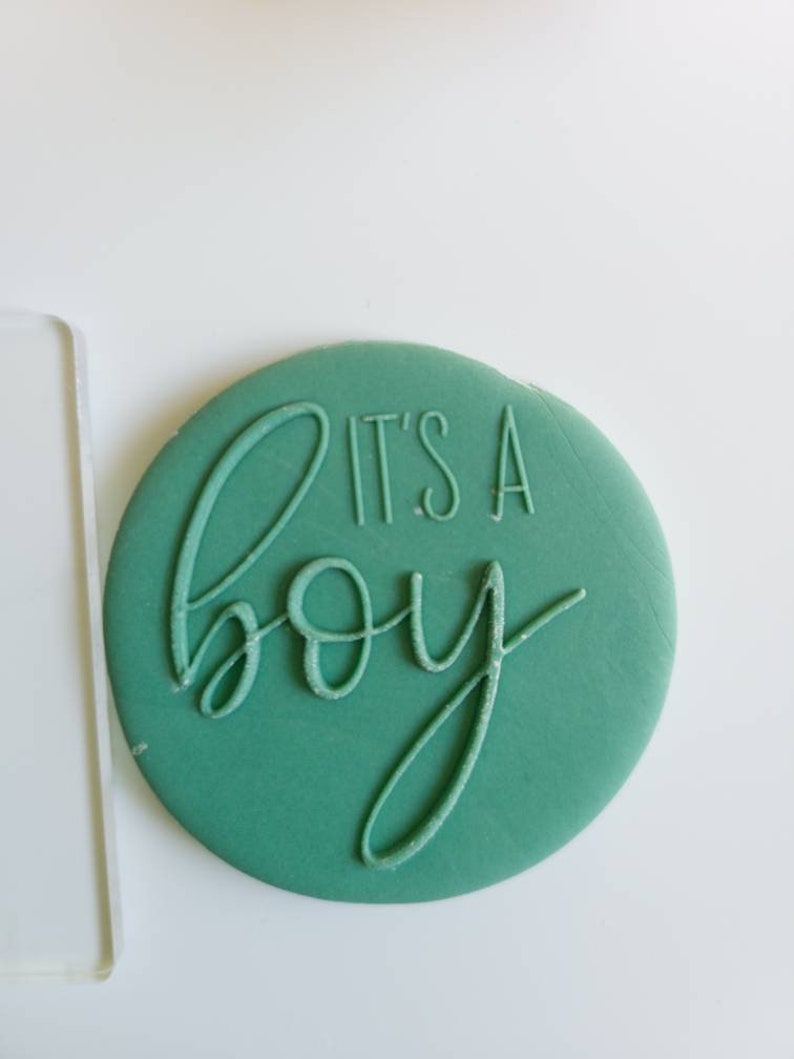 Op de afbeelding: Een ronde sticker in tealblauw met de tekst "It's a boy" in wit.