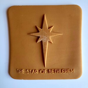Op de afbeelding: Een bruine rubberen stempel met een reliëfbeeld van een ster met acht punten en de tekst "THE STAR OF BETHLEHEM".