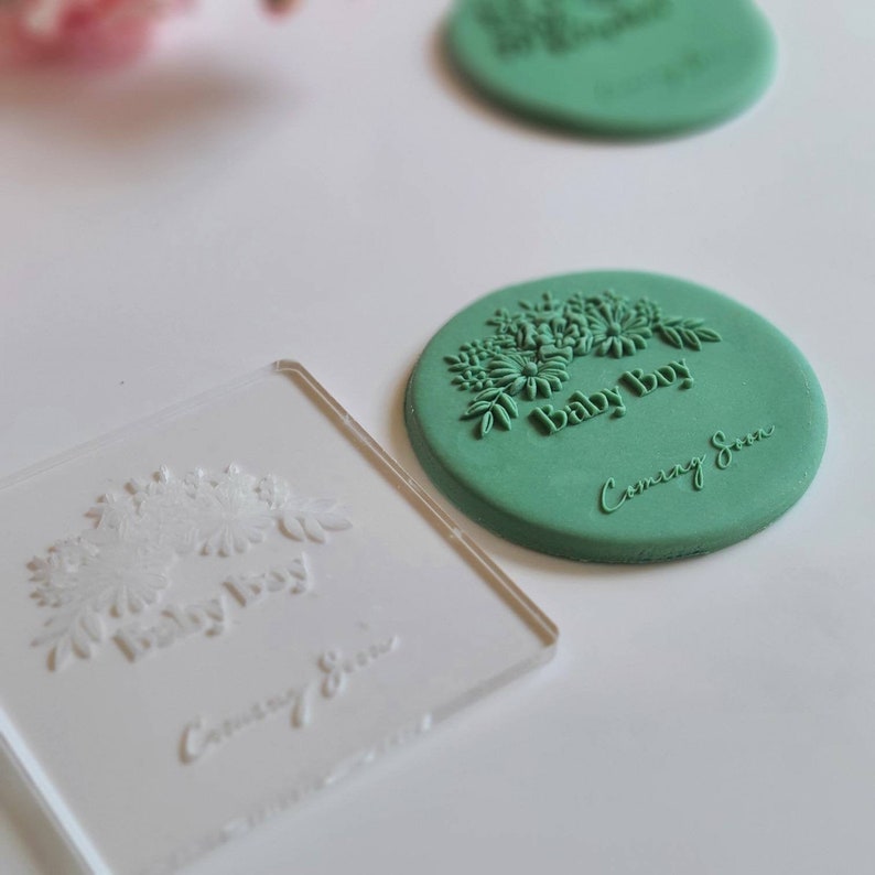 May include: A green polymer clay stamp with a floral design and the text "Baby Boy Coming Soon".