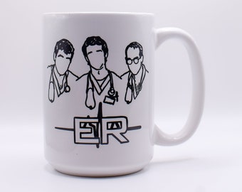 May include: White ceramic mug with a black outline of three doctors and the text "ER" on the front.