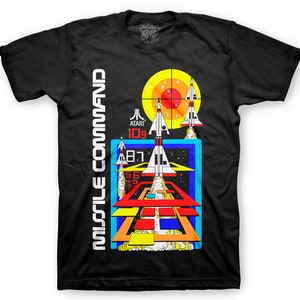 May include: Black t-shirt with a retro video game graphic of Missile Command. The graphic features a red target, three white spaceships, and a blue and orange background.