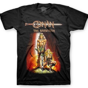 May include: Black t-shirt with a graphic of Conan the Barbarian and a woman standing in front of a fiery background. The text "Conan The Barbarian" is printed above the graphic.