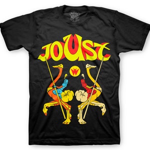 May include: Black t-shirt with a yellow, red, and blue graphic of two ostriches jousting with spears. The text "Joust" is above the ostriches in a yellow, red, and blue font.