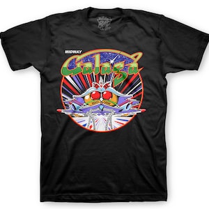 May include: Black t-shirt with a colorful graphic of a spaceship from the classic arcade game Galaga. The graphic includes the text "MIDWAY" and "Galaga".