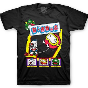 May include: Black t-shirt with a retro video game graphic of Dig Dug. The graphic features the main character, Dig Dug, and the enemies Pooka and Fygar. The text "Dig Dug" is in a colorful pixelated font.