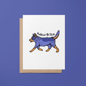 Puede incluir: Una tarjeta blanca con un perro de dibujos animados azul y naranja caminando y el texto "ANKLE BITER" encima.