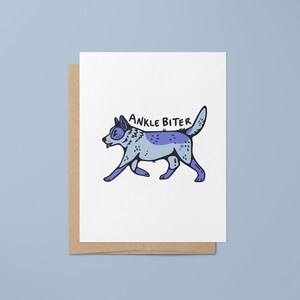 Puede incluir: Una tarjeta blanca con un perro de dibujos animados azul y morado caminando con el texto "ANKLE BITER" arriba.