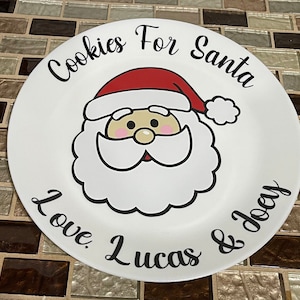 May include: White ceramic plate with a cartoon image of Santa Claus with the text "Cookies For Santa Love Lucas & Joey"
