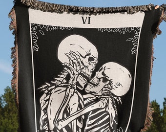 May include: Black and white tapestry featuring a tarot card design of two skeletons embracing. The card is labeled "VI THE LOVERS".