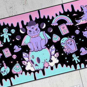 Könnte beinhalten: Eine schwarze und pinkfarbene Mausmatte mit einem tropfenden Maldesign. Sie zeigt eine lila Katze mit Flügeln, einen Schädel und andere gruselige und niedliche Illustrationen. Der Text "Shroom Queens" ist im Design sichtbar.