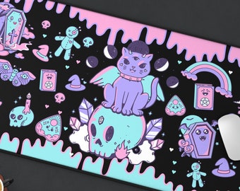 May include: A black and pink mousepad with a cute, spooky design. It features a cat with a skull, a rainbow, a coffin, and other spooky elements.