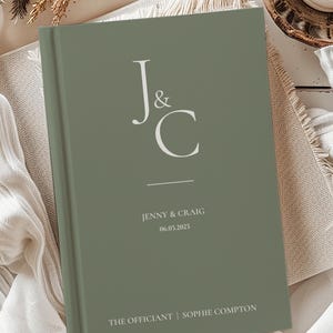 May include: A sage green hardcover journal with the initials "J&C" in white, the names "Jenny & Craig" and the date "08.03.2027" in white, and the text "THE OFFICIANT | SOPHIE COMPTON" in white.
