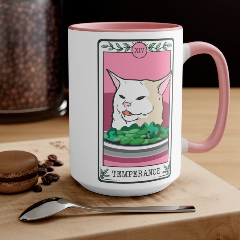 May include: White ceramic mug with a pink rim and handle. The mug features a white cat with a surprised expression, holding a bowl of green vegetables. The image is styled as a tarot card with the text "XIV TEMPERANCE" at the bottom.