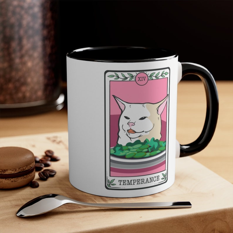 May include: White ceramic mug with a black rim and handle. The mug features a white cat with a pink background and the text "XIV TEMPERANCE" in black.