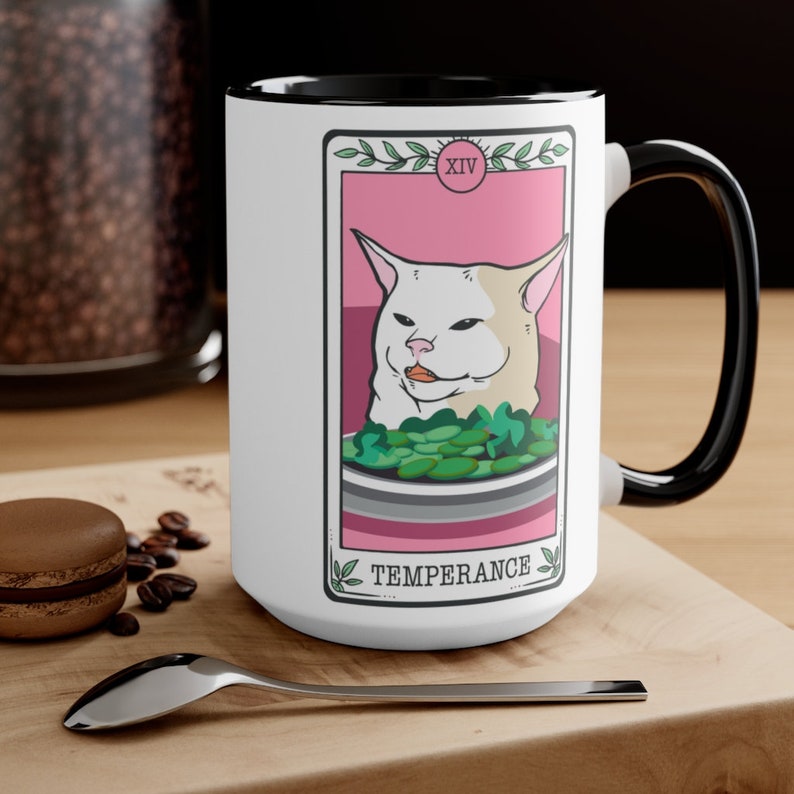 May include: White ceramic mug with a black rim and handle. The mug features a tarot card design with a white cat meme and the text "XIV TEMPERANCE".