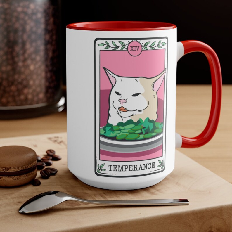 May include: White ceramic mug with a red rim and handle. The mug features a white cat with a pink background and the text "XIV TEMPERANCE" in a black font.