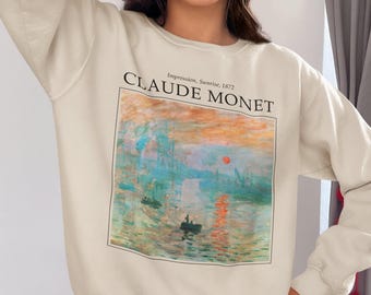 May include: A beige sweatshirt with a print of Claude Monet's Impression, Sunrise, 1872 painting. The text "Impression, Sunrise, 1872" and "Claude Monet" are printed below the painting.