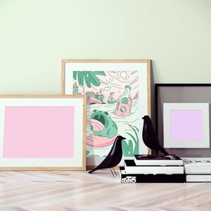 Peut inclure: Trois illustrations encadr&eacute;es, l'une avec un fond rose, l'autre avec un fond violet et la derni&egrave;re avec une grenouille de dessin anim&eacute; et une bouteille. Deux figurines d'oiseaux noirs sont devant les cadres.