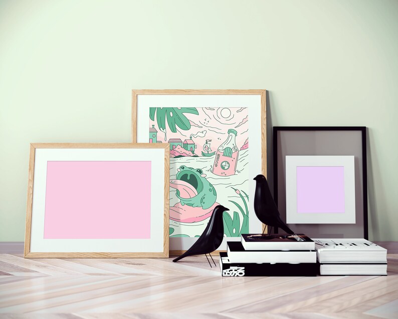Peut inclure: Trois illustrations encadr&eacute;es, l'une avec un fond rose, l'autre avec un fond violet et la derni&egrave;re avec une grenouille de dessin anim&eacute; et une bouteille. Deux figurines d'oiseaux noirs sont devant les cadres.