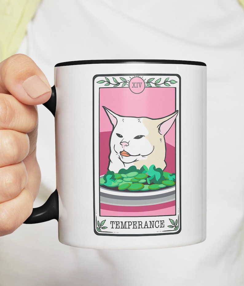 May include: White ceramic mug with a black rim and handle. The mug features a pink and white tarot card design with a white cat and the text "XIV TEMPERANCE".