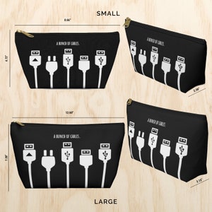 May include: Two black zippered pouches with white text that reads "A bunch of cables." The pouches are shown in two sizes, small and large, with measurements in inches. The pouches feature a design of five white cables with different connectors.