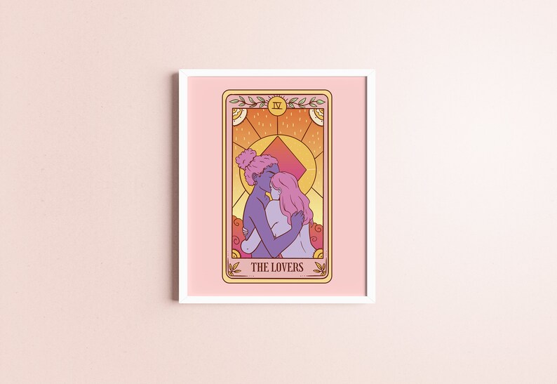 Op de afbeelding: Ingelijste kunstafdruk van een tarotkaart met twee figuren die elkaar omarmen, met de tekst "THE LOVERS". Het kunstwerk gebruikt een warm kleurenpalet met roze, oranje en paarse tinten. De afdruk is ingelijst met een witte rand.