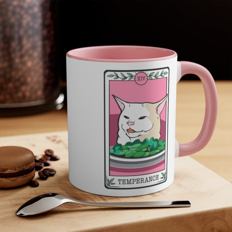 May include: White ceramic mug with a pink rim and handle. The mug features a tarot card design with a white cat and the text "TEMPERANCE" and "XIV".
