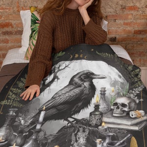 K&ouml;nnte beinhalten: Eine Schwarzwei&szlig;illustration eines Rabens, der auf einem Felsen sitzt, mit einem Sch&auml;del, Kerzen und Zaubertrankflaschen, die ihn umgeben. Der Rabe ist vor dem Hintergrund eines Vollmonds und eines dunklen Waldes platziert.
