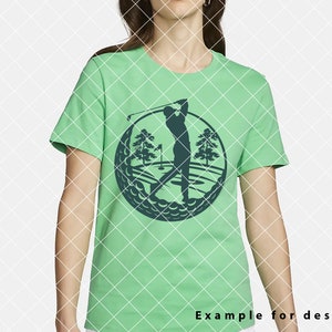 May include: A green t-shirt with a dark blue silhouette of a golfer swinging a club on a golf course. The golfer is in the center of a circle made of golf balls.