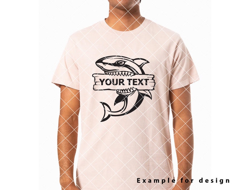 May include: A black and white illustration of a shark with its mouth open, biting a wooden sign that says "YOUR TEXT". The shark is on a light pink t-shirt.